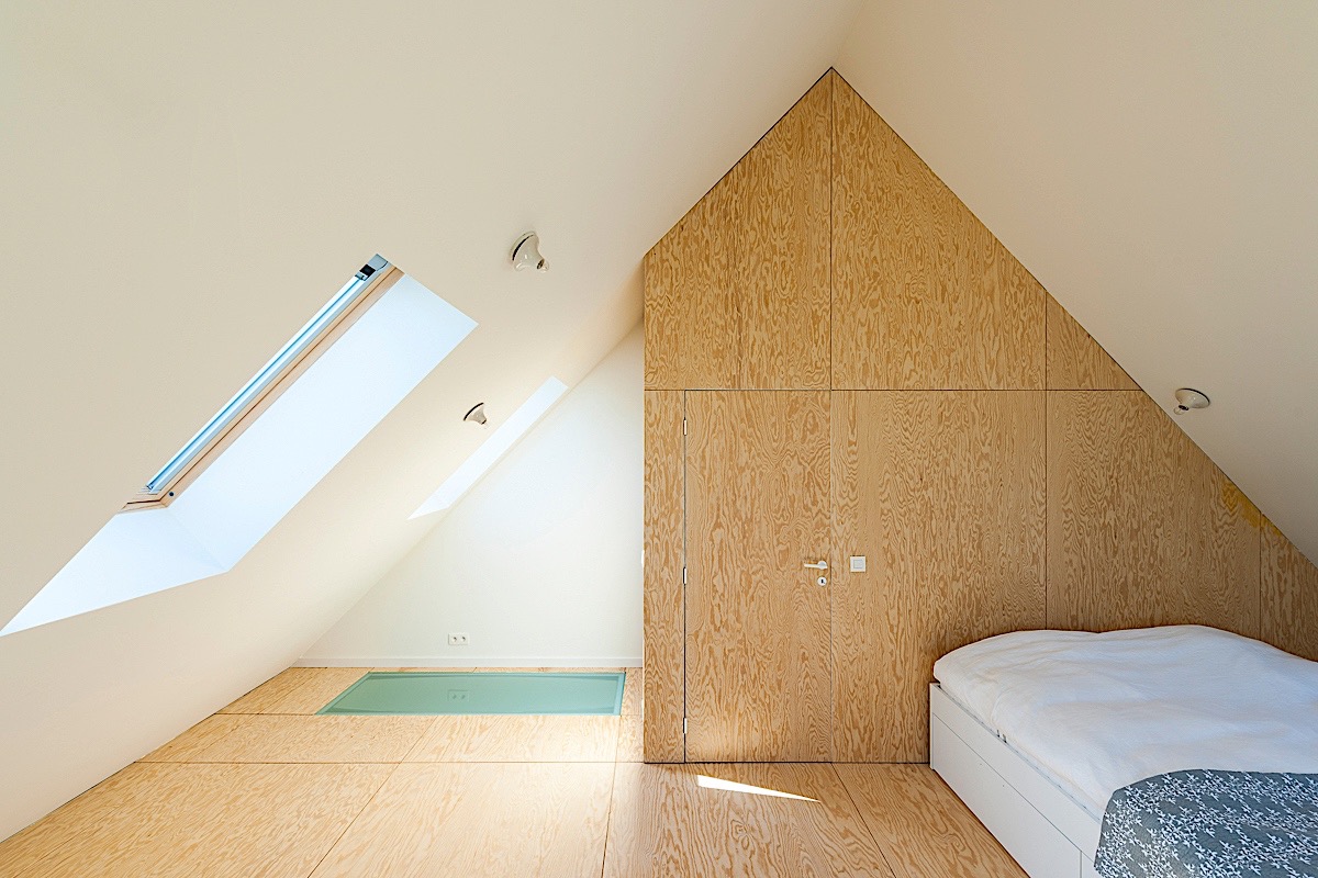 Doorgetrokken materialengebruik in vloer en wand zorgt voor harmonie. De deur geeft toegang tot de trap en opbergruimte.